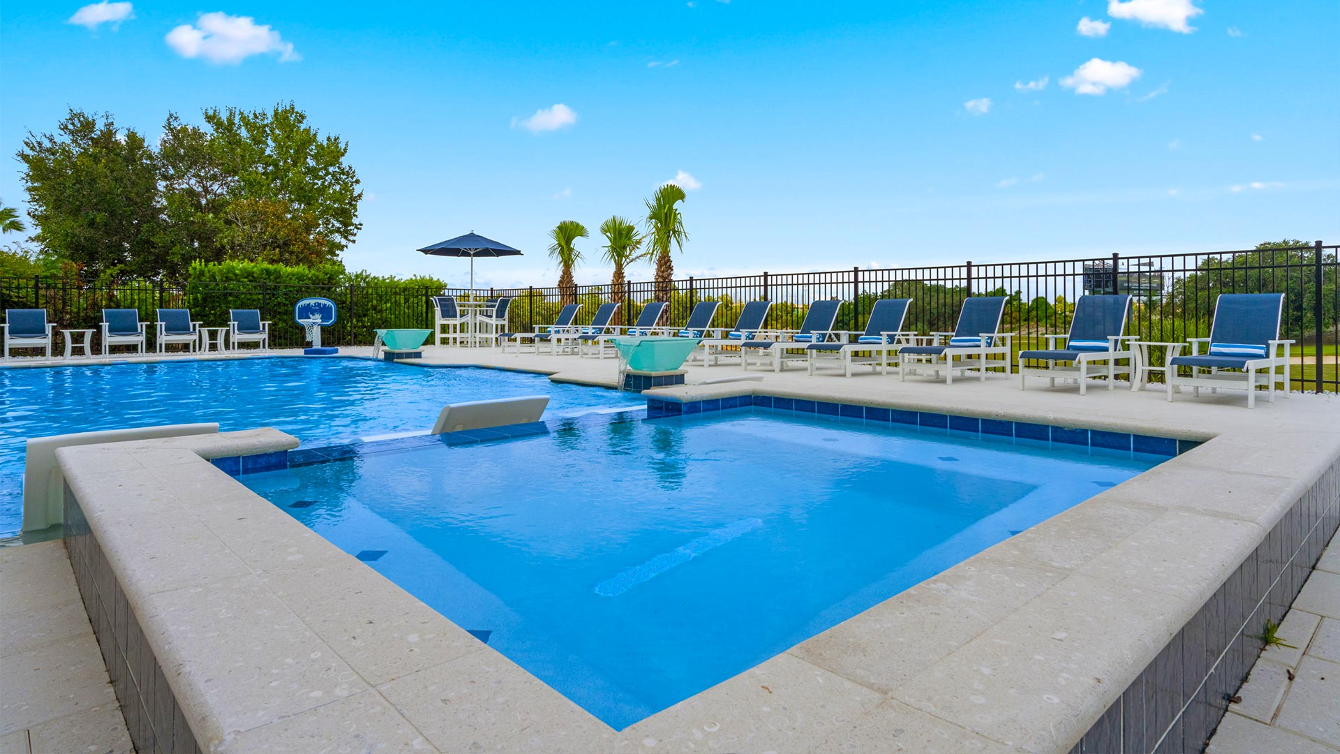 Spillover Spa Hot Tub Next To Backyard Pool With Cushioned Chaise Loungers