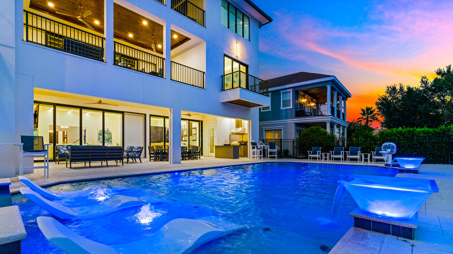 Backyard Pool At Sunset With Decorative Fountains And Three Sun Shelf Loungers